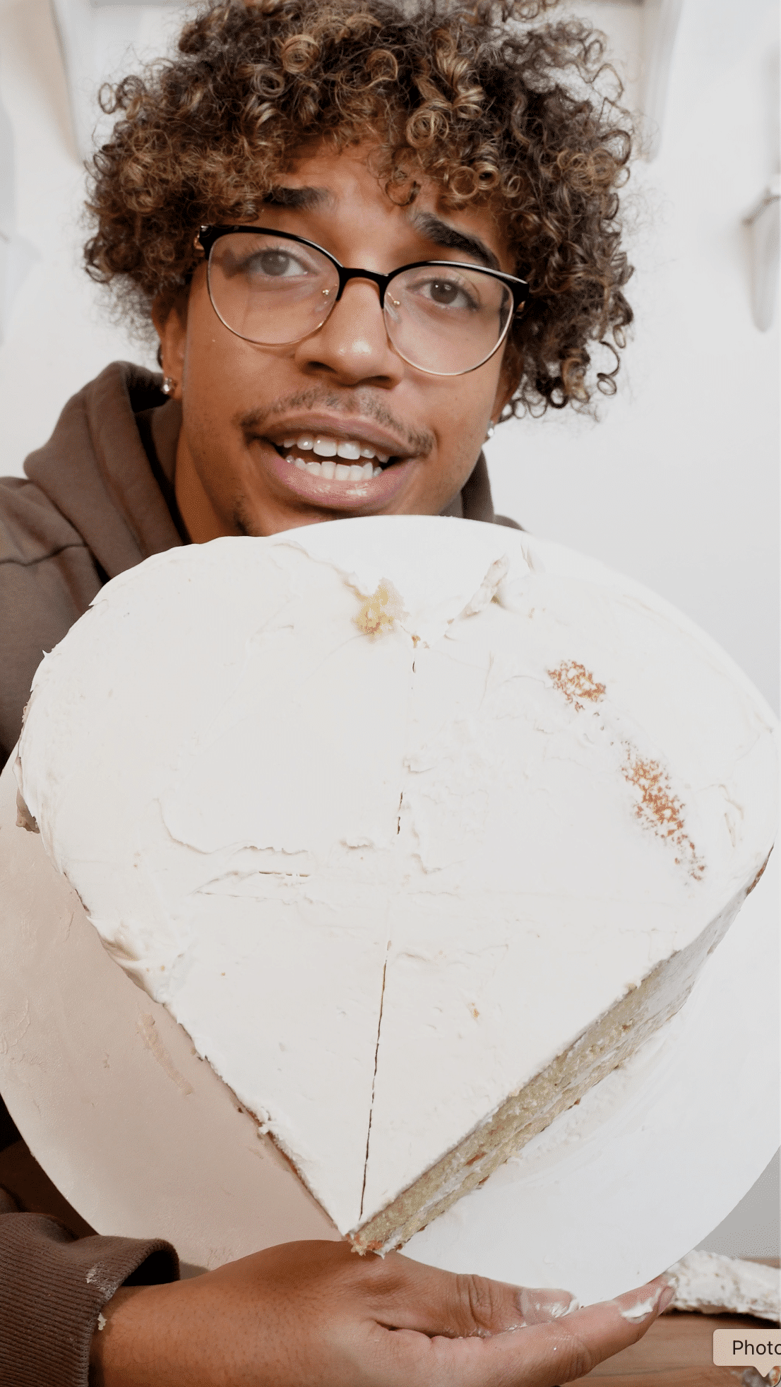 Baker holding a fully carved heart cake, showing the top view with the heart shape clearly formed.